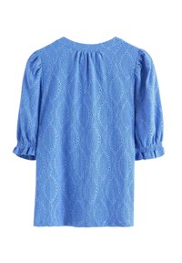 Ljusblå blus i öglat tyg med puffiga trekvartsärmar och mönster av diamantformade urtag.