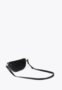 Svart läder axelväska med en rundad form, med en lång justerbar rem och ett blixtlås som stängning. Belägen mot en ljus bakgrund.