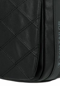 Borsa nera in pelle con un motivo trapuntato, texture liscia e logo in rilievo. Caratterizzata da una forma strutturata e delicati accenti metallici.