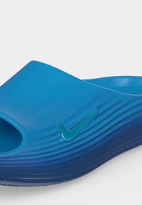 Μπλε σαγιονάρα Nike slide με υφή στη σόλα και ανάγλυλο λογότυπο Nike swoosh στο πλευρό.