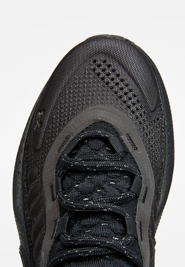 Scarpe sportive nere con tomaia in rete testurizzata, punta rinforzata e lacci neri piatti con sottili accenti riflettenti.