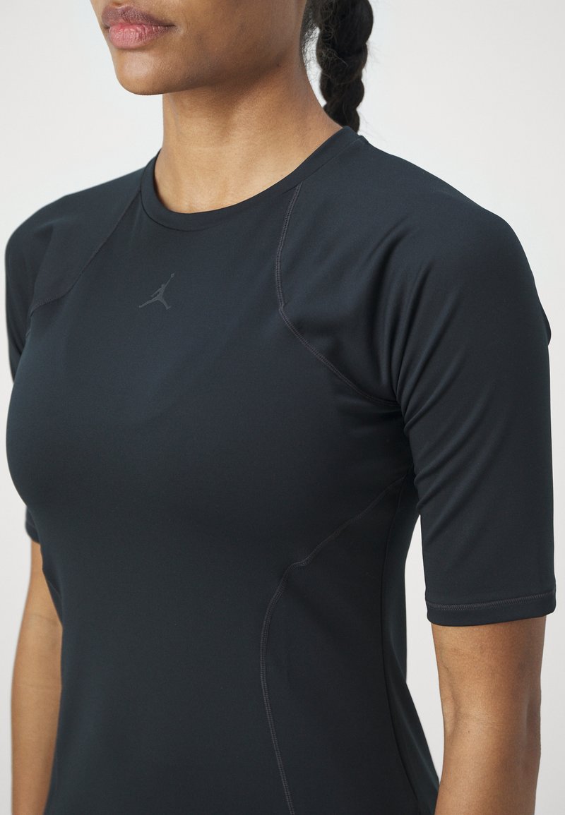 Camiseta deportiva negra de manga corta, hecha de un material elástico. Presenta una textura suave y un logotipo sutil en el pecho.