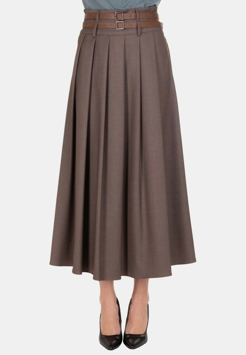 Gonna midi plissettata marrone con cintura a doppia fibbia, indossata con décolleté nere con punta appuntita su sfondo neutro.