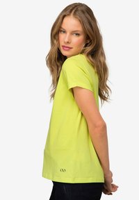 T-shirt verde lime a maniche corte con una vestibilità comoda, caratterizzato da un dettaglio del logo ricamato sull'orlo e un tessuto in cotone morbido.