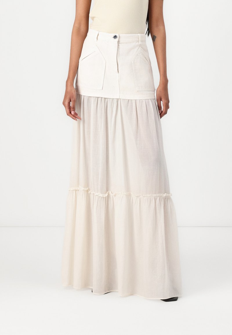Long skirt in cream color con un top strutturato e due tasche frontali, realizzata in un materiale simile al denim, con una parte inferiore a strati fluida.
