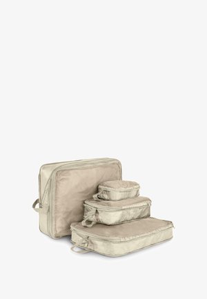 Set aus vier Reisekompressionstaschen aus weichem, cremefarbenem Stoff. Enthält eine große und drei kleinere Taschen, alle mit Reißverschlüssen und Griffen.