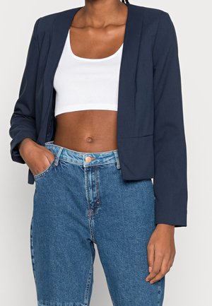 Blazer cropped marine à manches longues, en tissu lisse, avec une coupe décontractée et un devant ouvert, associé à un short en denim taille haute.