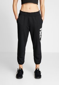 Zwarte sweatpants met een elastische tailleband, taps toelopende boorden en het "PUMA"-logo in het wit op het linkerbeen. Het materiaal lijkt zacht en rekbaar.