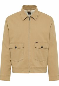 Beige Jacke mit Reißverschluss vorne, spitzem Kragen und zwei Brusttaschen. Hergestellt aus strapazierfähigem Stoff mit strukturiertem Futter. Mit schwarzen Knöpfen.