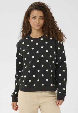 Mustvalge täpikestega must fliis, ümar kaelus, soonikkoes varrukateotsad ja serv. Pehme kangas ja lõdvestunud istuvus.