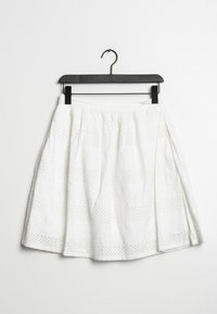 Vit bomullskjol med en utsvängd form, med horisontella ränder av spets och enfärgad tyg. Designad med ett rynkat midjeband och en hänge.