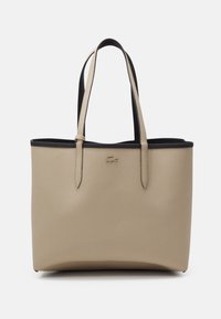 Sac fourre-tout en cuir beige avec une surface texturée, une bordure supérieure noire et des poignées doubles. Présente un logo discret sur le devant.