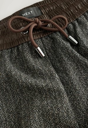 Gray houndstooth-patterned shorts with a brown elastic waistband and drawstring. Features silver metal accents on drawstring ends.