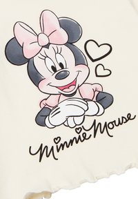 Bílý bavlněný tričko s grafikou kreslené postavičky s růžovou mašlí, černými ušima a srdíčkovými akcenty; pod tím nápis "Minnie Mouse".