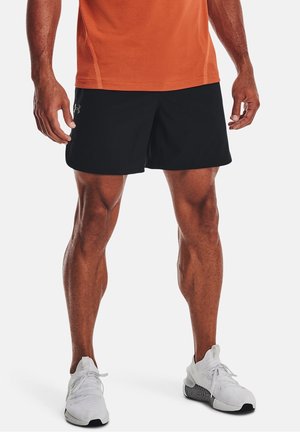 Schwarze athletische Shorts mit glatter Textur, versehen mit einem Logo auf der linken Seite, kombiniert mit weißen Schnürsneakern.