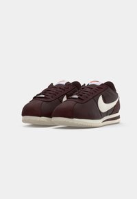 Scarpe da ginnastica bordeaux realizzate in suede e pelle con il logo Nike bianco, punta rotonda, lacci piatti e suola in gomma testurizzata.