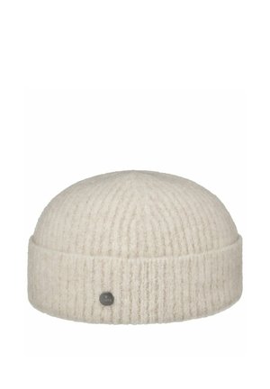 Cream-colored ribbed knit beanie with a folded cuff and a small round metal logo badge on the front.