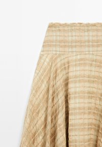 Beige karierte Rock mit hoher Taille, gefertigt aus einem strukturierten Stoff mit dezentem Glanz. Das Material hat einen weichen, fließenden Fall.