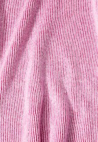 Strukturerad tyg med växlande ljusrosa och vita vertikala ränder. Materialet verkar mjukt med en ribbad yta.
