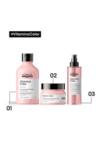 Trois produits de soin capillaire : une bouteille de shampooing rose, un pot de masque rose avec un couvercle noir, et une bouteille de spray rose. Tous étiquetés "Vitamine Color."