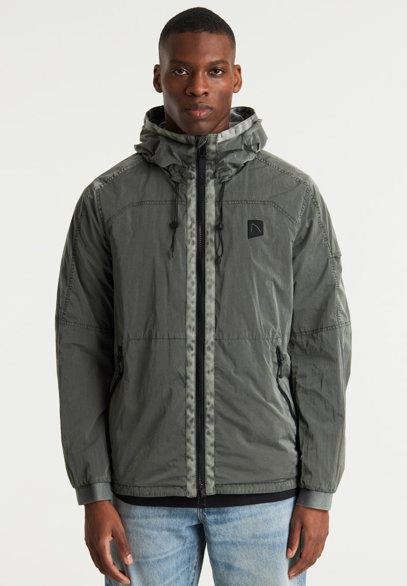 Chaqueta con capucha gris hecha de material ligero, con cremallera completa, capucha ajustable y bolsillos laterales. Acabado texturizado con parche de logo.