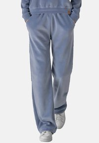 Blauwe sweatpants van zachte stof, met een relaxte pasvorm, elastische tailleband, zijzakken en een subtiele glans. Gepaard met witte sneakers.
