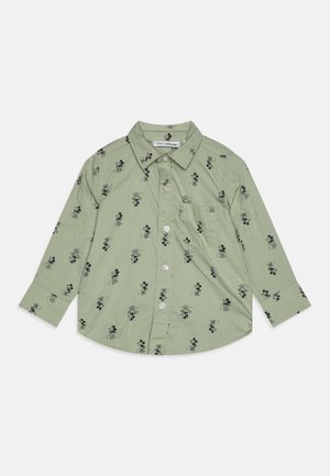 Camisa de botón verde claro con patrones de Mickey Mouse en negro, mangas largas, cuello y un bolsillo en el pecho izquierdo con dobladillo redondeado.