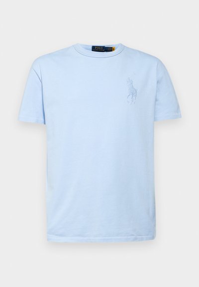 T-shirt de algodão azul claro com decote redondo e mangas curtas. Apresenta um logótipo bordado no lado esquerdo do peito. Textura suave.