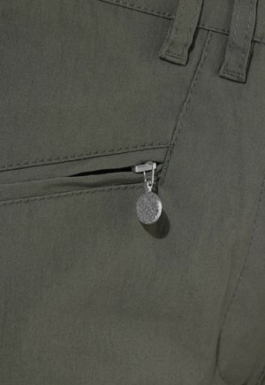 Detailní záběr tmavě zelené látky s částečně otevřeným kapsovým zipem a kulatým stříbrným jezdcem se vzorovaným povrchem.