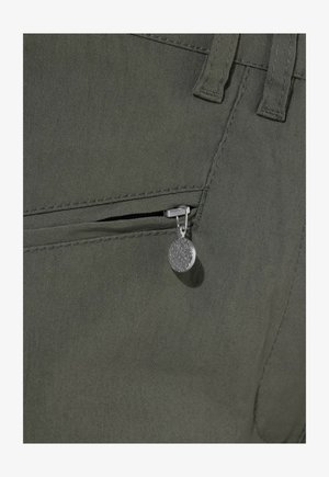 Primo piano di tessuto verde scuro con una tasca con cerniera parzialmente aperta e un cursore rotondo argentato con motivo strutturato.