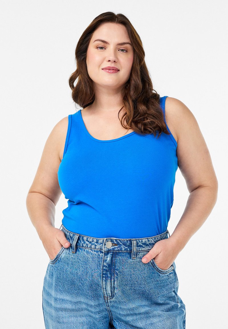 Plava majica bez rukava izrađena od mekanog materijala s okruglim izrezom, uparena s svijetloplavim trapericama visoki struk s bočnim džepovima.