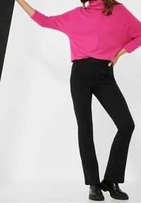 Rosa ribbad polokragetröja kombinerad med svarta figurnära byxor. Byxorna har en slät textur och rak bendesign. Svarta ankelboots syns.