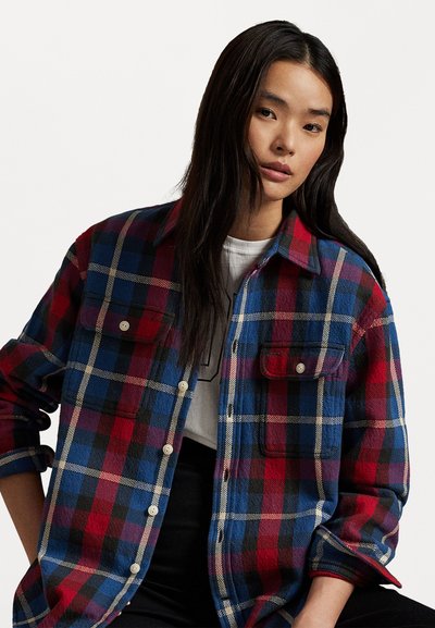 Red and blue plaid flannel shirt with two chest pockets, button front, and long sleeves. Soft texture and visible stitching details.