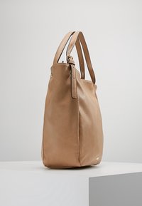 Borsa tote in pelle tan con due manici a spalla, texture liscia, design leggermente morbido e un piccolo accent dorato alla base.