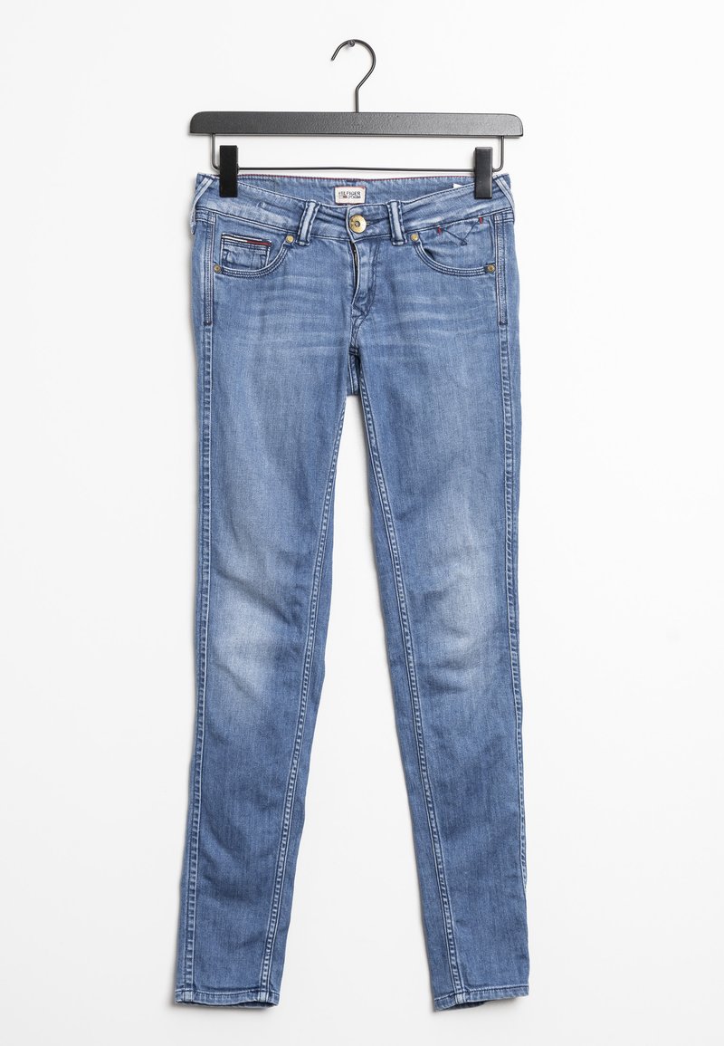 Jeans skinny de mezclilla azul con un clásico diseño de cinco bolsillos, frente sin costuras y un ligero desvanecimiento, colgados en una percha de metal negro.