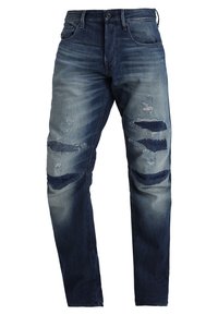 Haalarized dark blue denim farkut, joissa on useita kuluneita kohtia ja repeämiä etureisissä ja polvissa,napilla ja vetoketjulla kiinnitettävä.