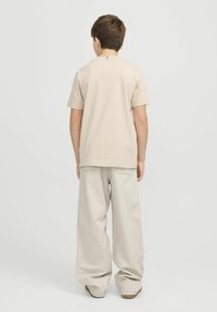 Beež puuvillane T-särk lühikeste varrukatega, koos laia joonega heleda beeži pükstega. Lihtne disain, ilma nähtavate mustrite või aktsentideta.