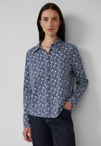 Hemd mit Knopfverschluss, das ein geometrisches blaues Muster auf wei�ßem Hintergrund präsentiert. Es besteht aus leichtem Stoff und hat einen klassischen Kragen sowie lange Ärmel.