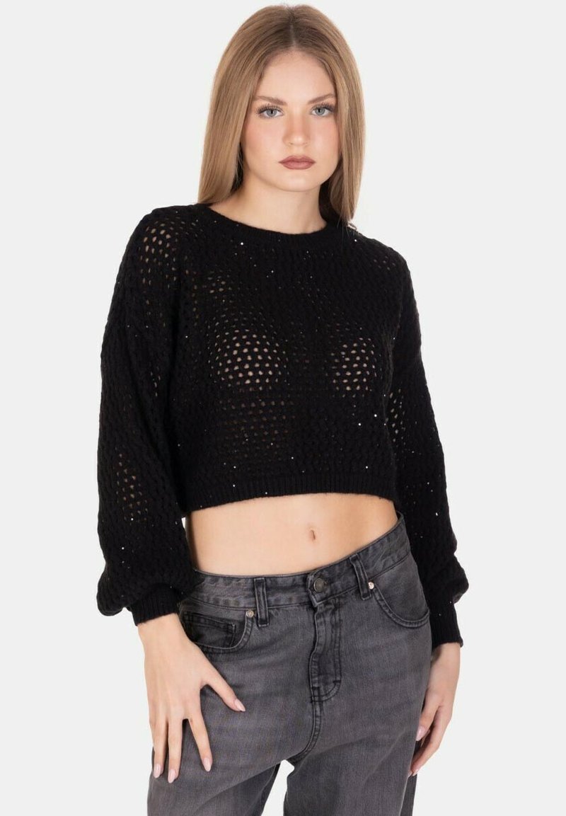 Maglione corto nero a maglia con trama aperta, maniche lunghe e dettaglio testurizzato. Indossato sopra jeans grigi a vita alta.