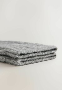 Coperta o plaid grigia lavorata a maglia con un motivo testurizzato, caratterizzata da accenti di filo metallico per un brillante effetto sottile; piegata con cura.