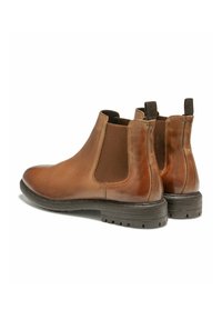 Bottines Chelsea en cuir marron avec des panneaux latéraux élastiques, des accents texturés et une semelle en caoutchouc robuste pour une meilleure traction. Fini lisse et languettes de tirage.