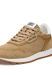 Tan suede sneaker with perforated texture, tan leather accents, beige laces, and a white heel. Features a prominent logo on the tongue.