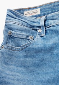 Vaqueros de mezclilla azul claro con una textura ligeramente deslavada, que cuentan con una cremallera y cierre de botón delantero, y un pequeño bolsillo para monedas con herrajes plateados.