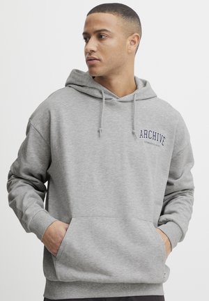 Grauer Hoodie mit einer frontalen Tasche, Kapuze mit Kordelzug und "ARCHIVE ESTABLISHED IN 1998" in marineblau gestickt. Weicher Stoff mit glatter Textur.