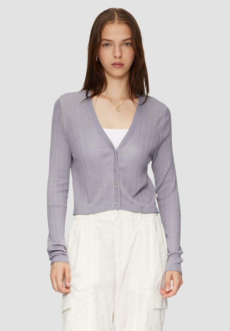 Lavendel geribde cardigan met een V-hals en knoopsluiting, met lange mouwen en een cropped ontwerp. Draag over een witte top.