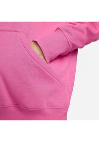 Hoodie i klarrosa bomull. Har en kängeru ficka och ribbade ärmslut, med en mjuk, texturerad yta.