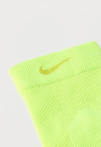 Φωτεινό κίτρινο καλτσάκι Nike με ribbed μανσέτα, υφασμένο σώμα με υφή και λογότυπο σε σκουρότερο κίτρινο στη μανσέτα. Κατάλληλο για αθλητική χρήση.