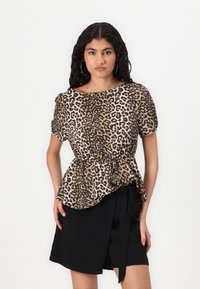 Top con stampa leopardata e maniche a palloncino corte, vita aderente e orlo fluido. Il tessuto è morbido, con sfumature di marrone e nero.