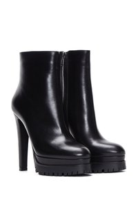 Zwarte leren enkelboots met een hoge hak. Voorzien van een rits aan de achterkant, een ronde neus en een gestructureerde plateauzool.