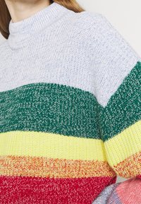 Suéter de punto con cuello alto. Cuenta con rayas horizontales en azul claro, verde, amarillo, rojo y naranja. Textura suave, diseño casual.